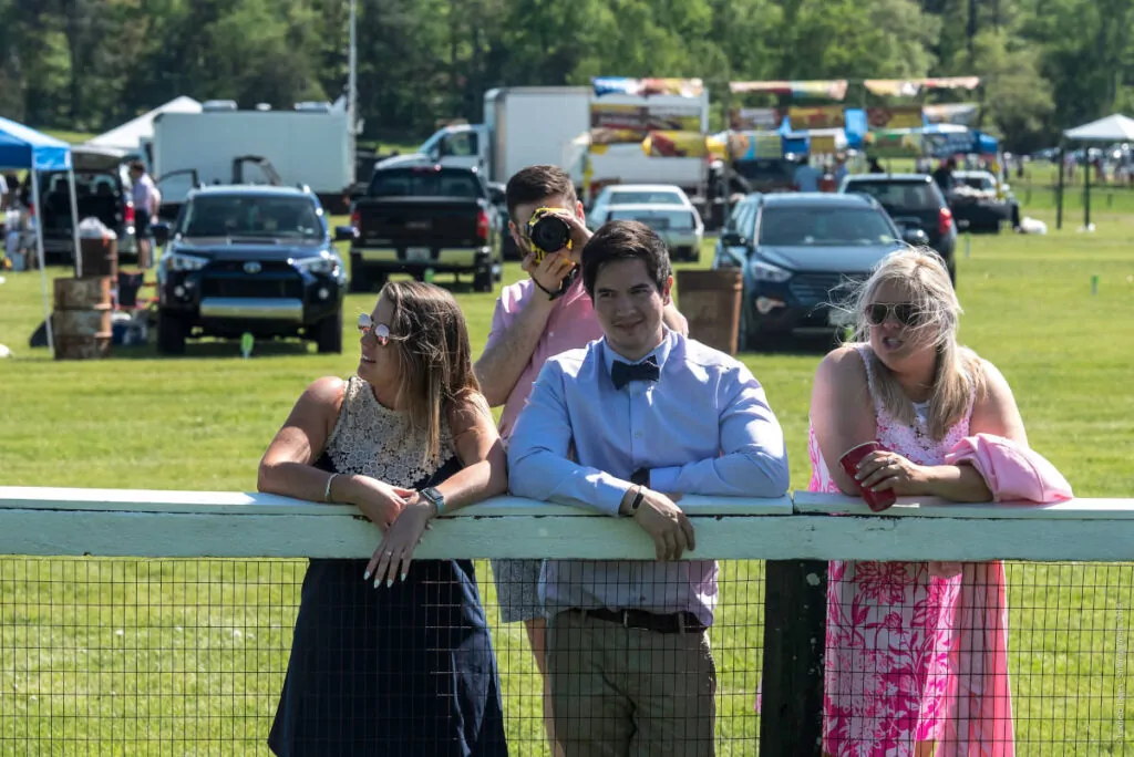 Well-Dressed onlookers lean on the track railing at Foxfield